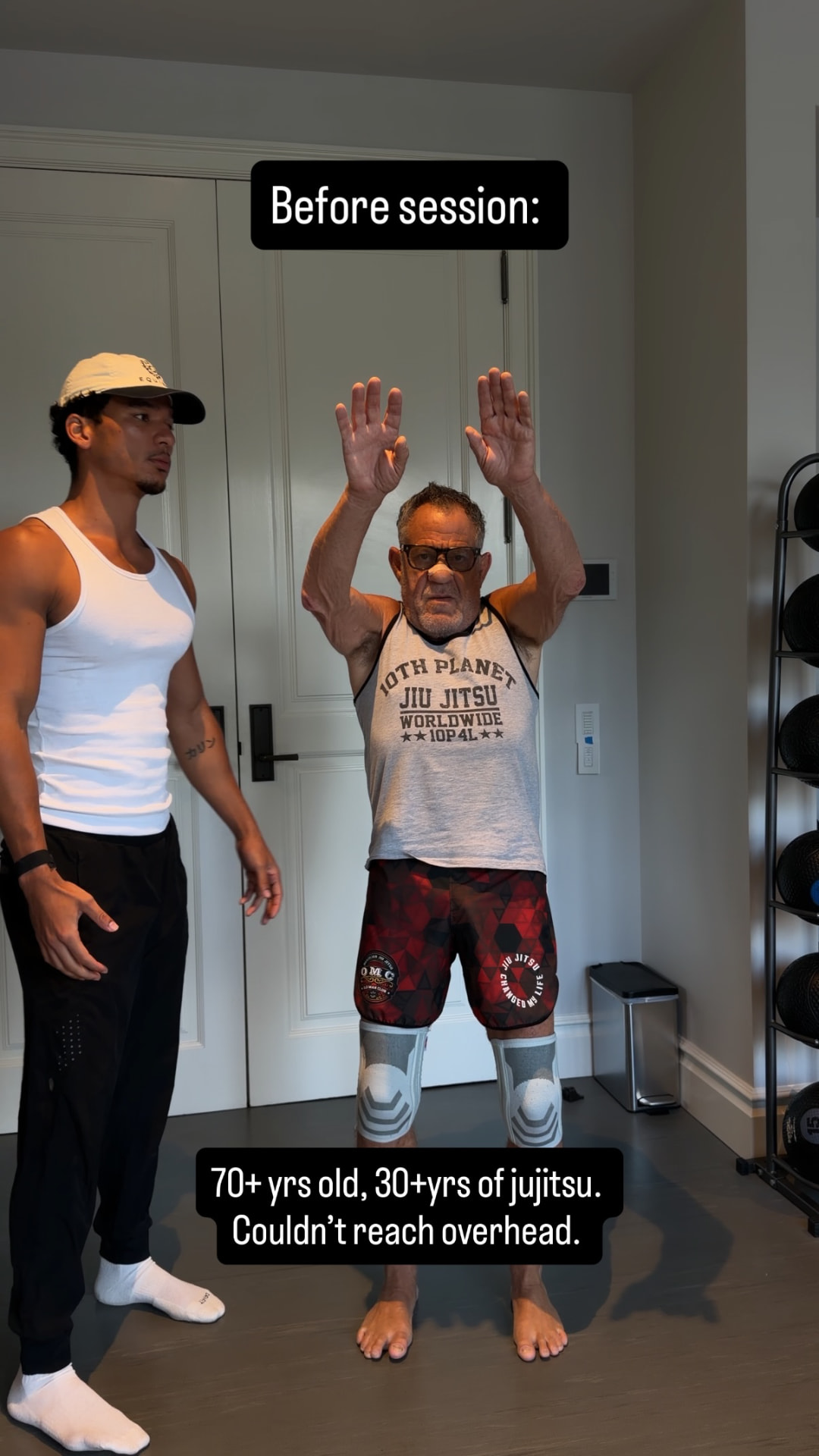 A jiu jitsu practitioner in his seventies reaching overhead before a mobility session, arms short of full height